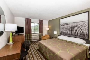 a hotel room with a bed and a desk and a television at Super 8 by Wyndham Storm Lake in Storm Lake
