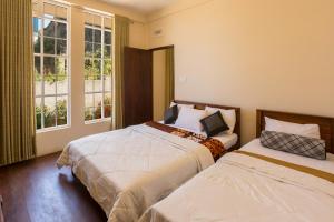 two beds in a room with two windows at Ovi Court City Apartments Nuwara Eliya in Nuwara Eliya