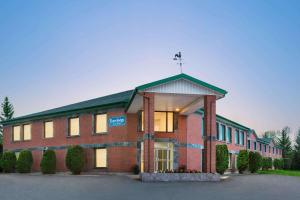 een groot bakstenen gebouw met een kruis bovenop bij Travelodge by Wyndham Rigaud in Rigaud