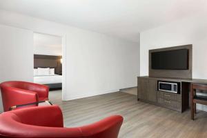 uma sala de estar com uma cadeira vermelha e uma televisão em Travelodge by Wyndham Rigaud em Rigaud