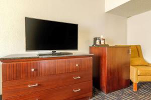 a television on top of a wooden dresser with a chair at Rodeway Inn Denver Downtown in Denver