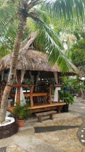 une cabane avec un banc et un palmier dans l'établissement Love's Beach & Dive Resort, à Moalboal