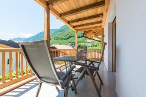 a chair and a table on a balcony with mountains at Eco Bnb & Apartments Bründlerhof in Marlengo