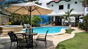- une table et des chaises avec un parasol à côté de la piscine dans l'établissement Love's Beach & Dive Resort, à Moalboal