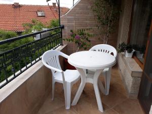 two white chairs and a white table on a balcony at Dom Shtakovi in Pomorie