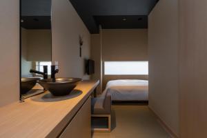 ein Bad mit einem Spülbecken und einem Bett in der Unterkunft ONSEN RYOKAN YUEN SHINJUKU in Tokio