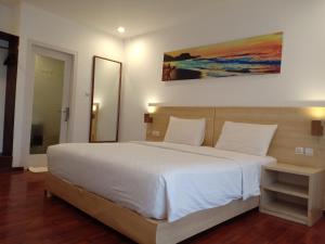 una camera da letto con un grande letto bianco e un dipinto sul muro di Villa PhyPhy a Gili Trawangan