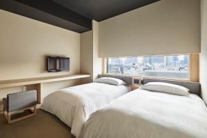 zwei Betten in einem Hotelzimmer mit Fenster in der Unterkunft ONSEN RYOKAN YUEN SHINJUKU in Tokio + 53 Fotos