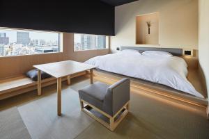 ein Schlafzimmer mit einem Bett, einem Schreibtisch und einem Stuhl in der Unterkunft ONSEN RYOKAN YUEN SHINJUKU in Tokio