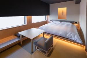 ein Schlafzimmer mit einem Bett, einem Tisch und einem Stuhl in der Unterkunft ONSEN RYOKAN YUEN SHINJUKU in Tokio