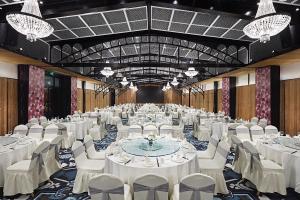 a banquet hall with white tables and chairs and chandeliers at Gallery F Hotel in Wuhan
