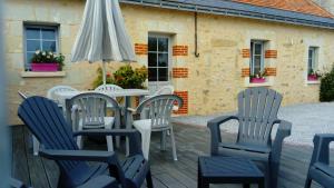 een tafel en stoelen op een terras met een paraplu bij La Vignellerie du Lac in Hommes