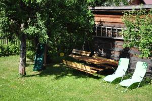 a bench and two chairs in the grass next to a building at Forester Apartment Zuberec in Zuberec +49 photos