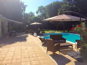 a patio with chairs and a pool with an umbrella at Roulotte de Dilou Noisette in Matha