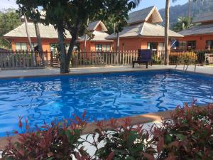 a large blue swimming pool in front of a house at Lanta Cottage - SHA Plus in Ko Lanta