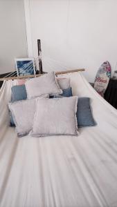 een wit bed met vier kussens erop bij Petit Bonheur in Oudenaarde
