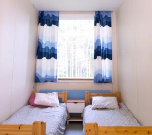 two beds in a room with a window at Nikkilän Elämyskylä in Saariharju