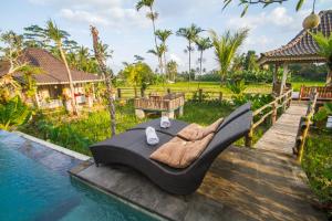 a couch sitting on a deck next to a pool at Uma Caming Villas & Gym in Tegalalang