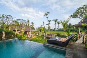 a resort with a pool with a reclining chair next to it at Uma Caming Villas & Gym in Tegalalang