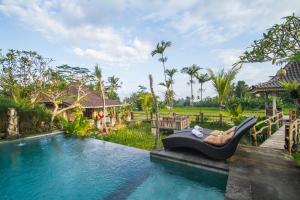 un complejo con una piscina con una silla reclinable al lado en Uma Caming Villas & Gym, en Tegalalang