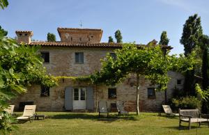 une ancienne maison en pierre avec des chaises en face de celle-ci dans l'établissement Il Casale del Duca, à Urbino