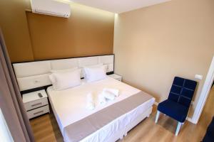 1 dormitorio con 1 cama blanca y 1 silla azul en Brilant Luxury Apartment, en Gjirokastra