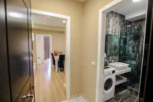 a bathroom with a sink and a washing machine at Brilant Luxury Apartment in Gjirokastër
