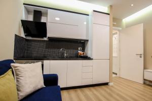 a kitchen with white cabinets and a blue couch at Brilant Luxury Apartment in Gjirokastër