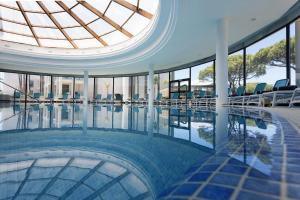 a swimming pool with chairs in a building with a domed ceiling at Hipotels Barrosa Park in Chiclana de la Frontera