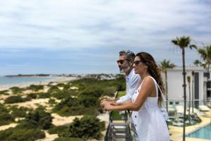 a man and a woman standing on a balcony overlooking the beach at Hipotels Barrosa Park in Chiclana de la Frontera