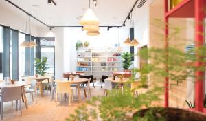 een restaurant met tafels, stoelen en ramen bij The Green Elephant Hostel & Spa in Maastricht