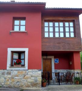 Casa roja con puerta y ventanas de madera en Pelayo I, en Poo de Cabrales