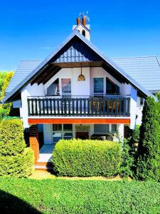 a large white house with a balcony and bushes at Holiday home Jarzębinowa in Rowy