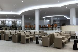a waiting room with chairs and tables and a bar at Hipotels Barrosa Park in Chiclana de la Frontera