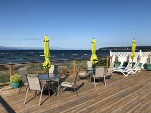 a deck with chairs and tables and yellow umbrellas at Buena Vista by the Sea in Qualicum Beach