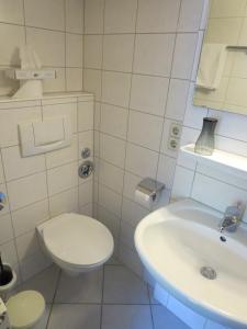 a white bathroom with a toilet and a sink at Der Gasthof in Alfdorf in Alfdorf