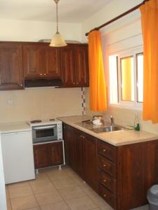 ニキアナにあるPHILIPPOS Hotel Apartmentsのキッチン(木製キャビネット、シンク付)