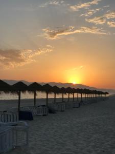 een zonsondergang op het strand met parasols bij Casa Braites T3 Soltroia Mar - Ar Condicionado - 5 minutos a pé da praia e a 12Km da Comporta in Troia