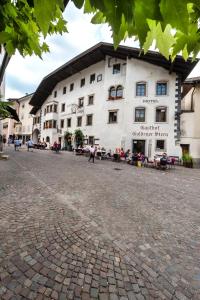 a large white building on a cobblestone street at Hotel Goldener Stern in Caldaro