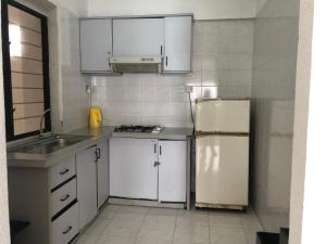 een keuken met witte kasten en een koelkast bij Sri Sayang Resort Service Apartment in Batu Ferringhi