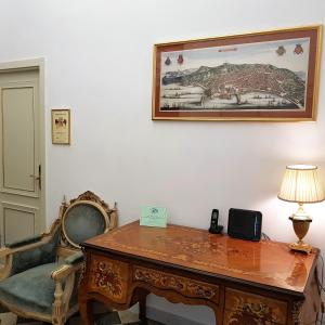 uma secretária e uma cadeira com um candeeiro e uma fotografia na parede em Residence San Mattia em Nápoles