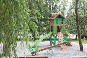 un parque infantil con una casa en el árbol y un tobogán en Hotel Vesna, en Truskavets