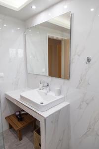 a white bathroom with a sink and a mirror at Iro's House in Nafplio