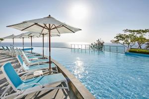a swimming pool with chairs and umbrellas at Lotte Resort Sokcho in Sokcho