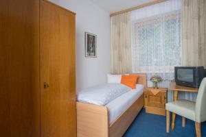 a small bedroom with a bed and a television at Pension Anneliese in Rauris