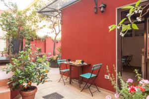 ローマにあるカーサ イン モンティの赤い壁の隣にテーブルと椅子付きのパティオ