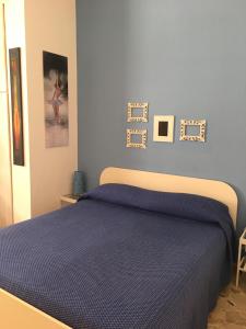 a bedroom with a bed with blue sheets and pictures on the wall at Antonio's House in Agrigento