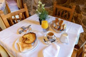 a table with a plate of bread and coffee and orange juice at Casa Rural La Chata by Vivere Stays in Valsain