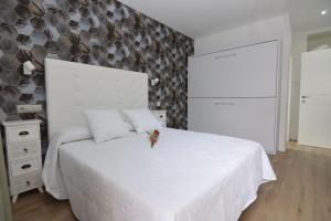 ein weißes Schlafzimmer mit einem weißen Bett und einer Wand in der Unterkunft Hotel Castillo Benidorm in Benidorm