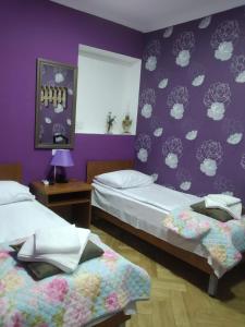 a bedroom with two beds and a purple wall at Tbilisi Downtown Guest House in Tbilisi City
